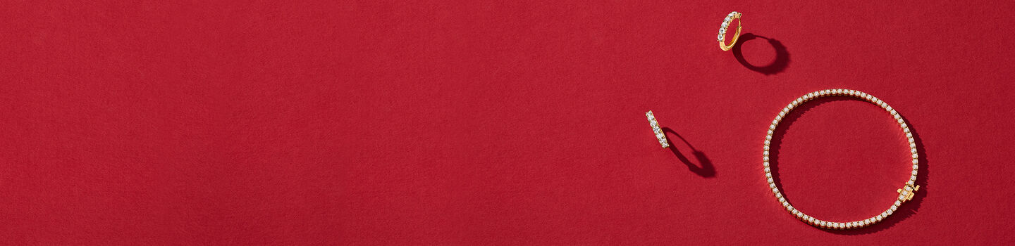 Birks gold and diamond earrings and bracelet on a red background.